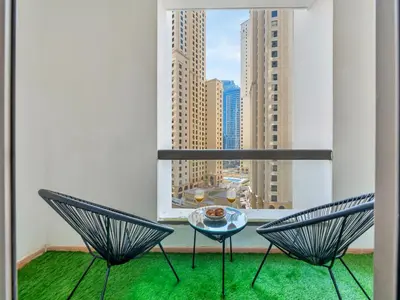 a balcony with two chairs and a table and a window at JBR Studio - Steps to Beach & Marina Walk - Pool & Gym in Dubai