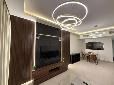 a living room with a large television and a dining room at Aesthetic Feel with Lake View in Dubai