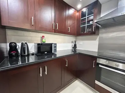 a kitchen with wooden cabinets and a microwave oven at Luxurious 1Bedroom Apt in 29 Boulevard - Downtown in Dubai