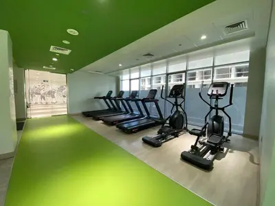 a gym with a row of treadms and elliptical machines at Bright and Stylish Studio - Azizi Aura in Dubai