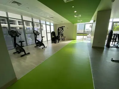 a gym with treadmills and exercise bikes in a room at Bright and Stylish Studio - Azizi Aura in Dubai