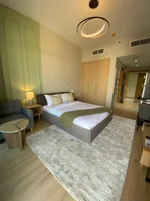 a bedroom with a large bed and a rug at Bright and Stylish Studio - Azizi Aura in Dubai