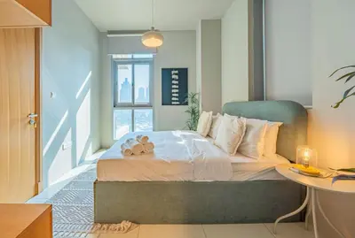 a bedroom with a bed with a table and a window at Stylish Two-BHK Apartment - Iris Blue, Marsa Dubai in Dubai
