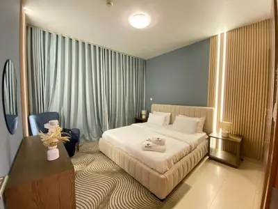 a hotel room with a bed and a table and a desk at Modern 2BR in Skycourt Tower A - Free Parking - Pool and Gym in Dubai