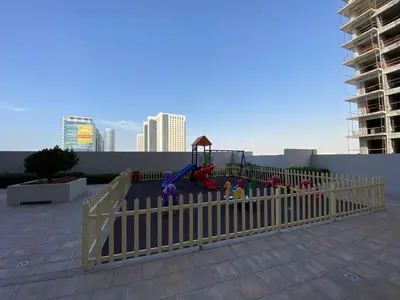 a fence with a playground on a rooftop at Two-Bedroom Apartment with Prime Metro Access in Dubai