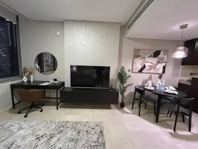 a living room with two tables and a flat screen tv at Elegant Studio in Difc - Skyline Views, Pool, Gym in Dubai