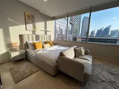 a bedroom with a bed and a couch and a large window at Elegant Studio in Difc - Skyline Views, Pool, Gym in Dubai