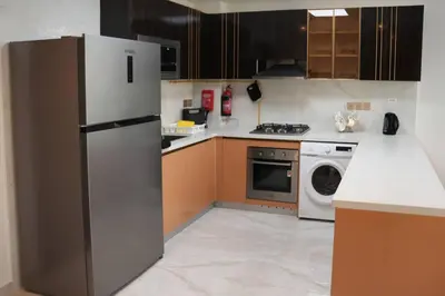 a kitchen with a refrigerator and a dishwasher at Fully Furnished 2-Bedroom Apt in Gemz by Danube in Dubai
