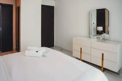 a bedroom with a white bed with a dresser and a mirror at Fully Furnished 2-Bedroom Apt in Gemz by Danube in Dubai