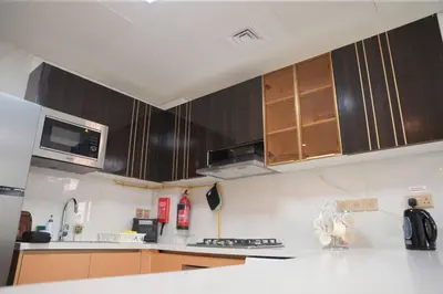 a kitchen with wooden cabinets and a white counter top at Fully Furnished 2-Bedroom Apt in Gemz by Danube in Dubai