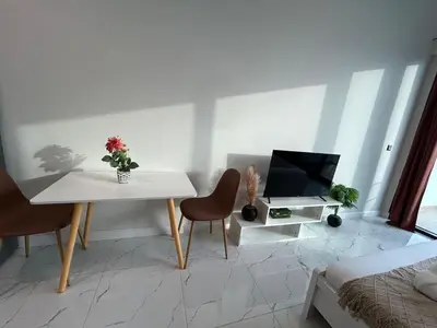 a living room with a white table and a television at Spacious 1BR - Alexis Tower 1 - Close to Metro in Dubai