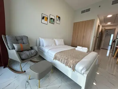 a bedroom with a large bed and a chair at Spacious 1BR - Alexis Tower 1 - Close to Metro in Dubai