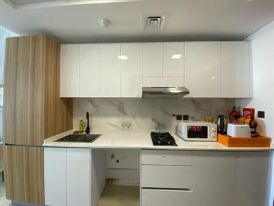 a kitchen with white cabinets and a sink and a microwave at Cozy Studio Apartment with Balcony in Dubai