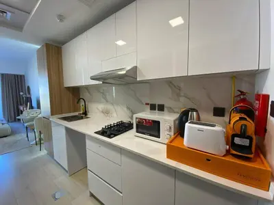 a kitchen with white cabinets and a counter top at Cozy Studio Apartment with Balcony in Dubai