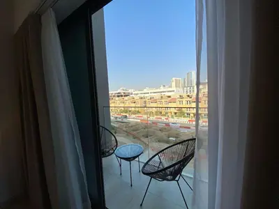 three chairs and a table on a balcony with a window at Cozy Studio Apartment with Balcony in Dubai