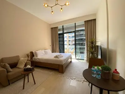 a bedroom with a bed and a couch and a table at Stylish studio with Pool and Gym access. in Dubai