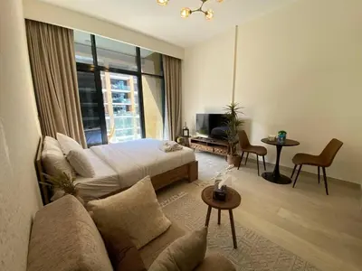 a bedroom with a bed and a couch and a tv at Stylish studio with Pool and Gym access. in Dubai