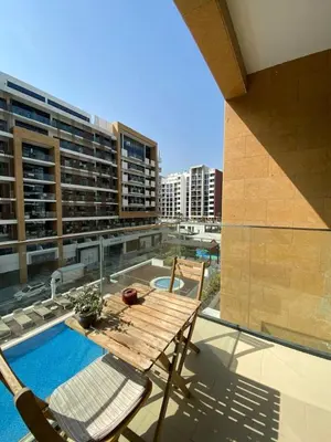 a patio with a wooden table and chairs on a building at Stylish studio with Pool and Gym access. in Dubai