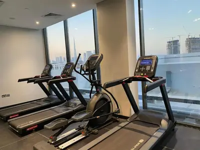 a gym with three tread machines in front of a window at Stylish studio with Pool and Gym access. in Dubai