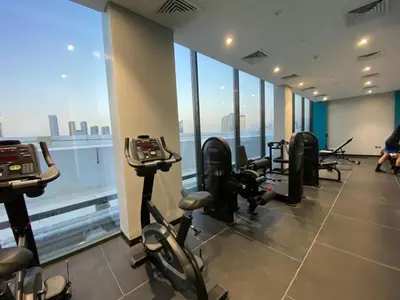 a gym with treadmills and exercise bikes in a building at Stylish studio with Pool and Gym access. in Dubai