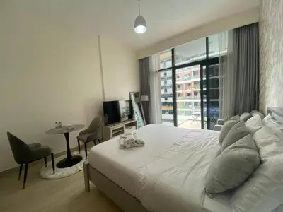 a bedroom with a large white bed and a window at Studio Apartment with Pool and Gym Access in Dubai