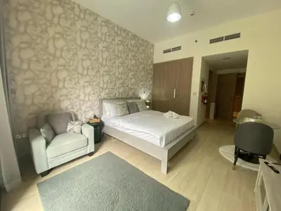a bedroom with a bed and a couch and a chair at Studio Apartment with Pool and Gym Access in Dubai