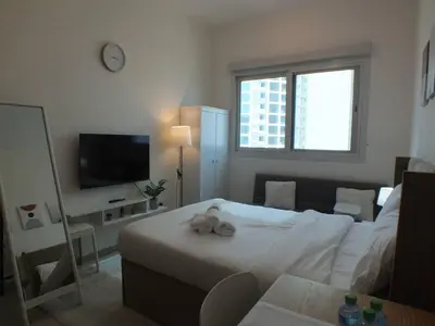 a living room with a bed and a television at Charming Studio Apartment in Jadaf in Dubai