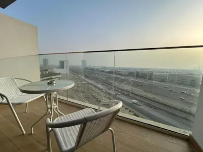 a balcony with a table and chairs and a view of a highway at Modern Studio Apt in Jabel Ali Near Metro in Dubai