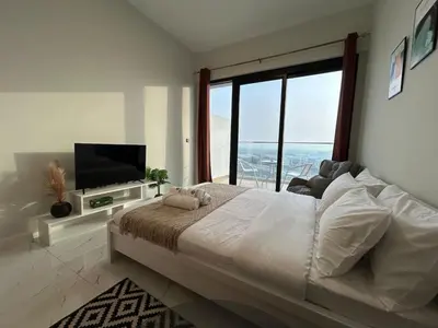 a bedroom with a large bed and a large window at Modern Studio Apt in Jabel Ali Near Metro in Dubai