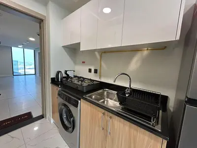 a kitchen with a sink and a washing machine at Modern Studio Apt in Jabel Ali Near Metro in Dubai