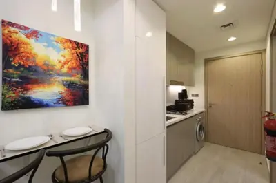 a kitchen with a painting on the wall and two chairs at Fully Equipped Studio in Meydan in Dubai