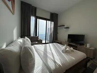 a bedroom with a white bed with two towels on it at Modern Studio Apt in Jabel Ali Near Metro in Dubai