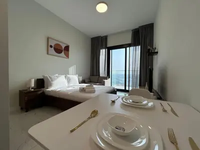 a hotel room with a bed and a table with plates on it at Modern Studio Apt in Jabel Ali Near Metro in Dubai