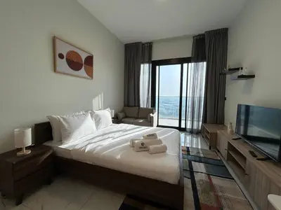 a bedroom with a large bed and a flat screen tv at Modern Studio Apt in Jabel Ali Near Metro in Dubai