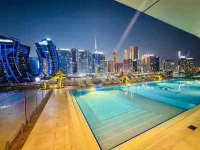 a large swimming pool with a city skyline at night at Luxe 1BR Hamilton Residency Business Bay with balcony in Dubai