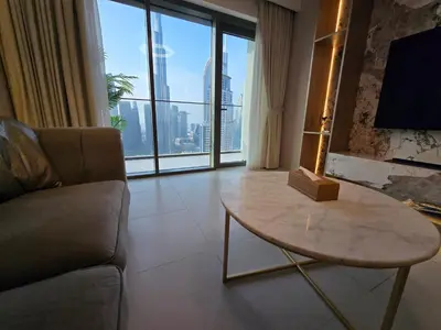 a living room with a couch and a table and a large window at Highend Luxury 2BR Direct Burj Khalifa & Fountain Views in Dubai