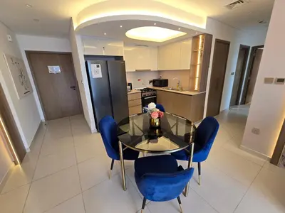 a dining room with a glass table and blue chairs at Highend Luxury 2BR Direct Burj Khalifa & Fountain Views in Dubai