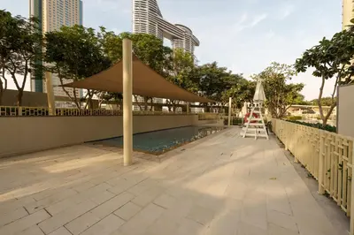 a patio with a large umbrella and a pool at Downtown Luxury Two Bedroom Apartment I Conntected To Dubai Mall And Metro I Steps Away From Burj Khalifa I by Luxury Space in Dubai