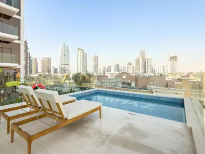 a balcony with a chair and a swimming pool at VayK - Bright and Modern One Bedroom in JVC in Dubai