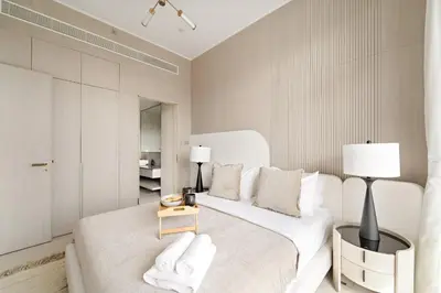 a bedroom with a large white bed with a table at VayK - Bright and Modern One Bedroom in JVC in Dubai
