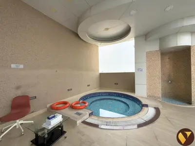 a large swimming pool with a red chair in a room at Vogue Arjan Siraj Tower near Miracle Garden and Dubai Hills Mall, One Bedroom Apartment with Large Balcony and City View, Access to all Amenities in Dubai