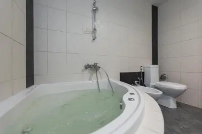 a bathroom with a tub filled with water with a toilet at Cloud 9 Room Marina in Dubai