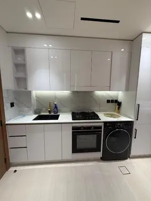 a kitchen with white cabinets and a stove and a dishwasher at Modern Studio Apartment In JVC in Dubai