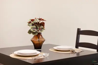 a table with two plates and a vase with flowers at Spacious & cozy Studio in Downtown! in Sabkhah