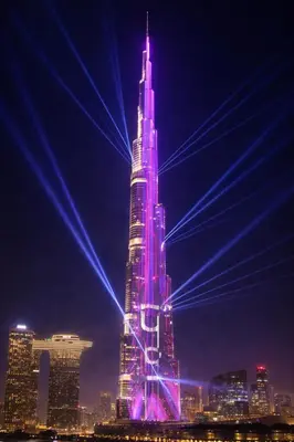 a tall skyscraper lit up in purple at night at Spacious & cozy Studio in Downtown! in Sabkhah