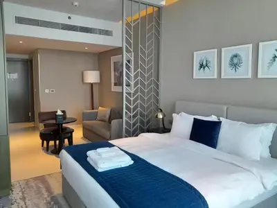 a bedroom with a large bed and a living room at Bright and Modern 1-Bed Studio with Sofa in DAMAC Prive in Dubai