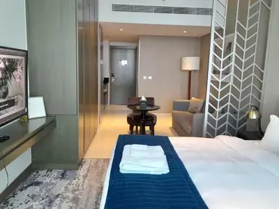 a hotel room with a bed and a table at Bright and Modern 1-Bed Studio with Sofa in DAMAC Prive in Dubai