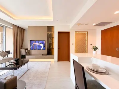 a living room with a dining table and a tv at Luxurious 1 BR Apt Kempinski Central Avenue in Dubai