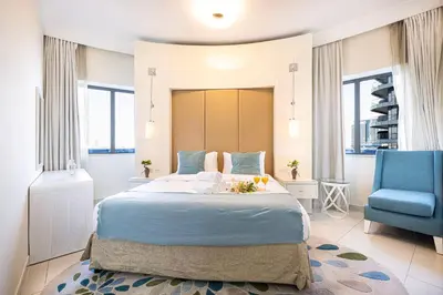 a bedroom with a large bed and a blue chair at Damac Maison Mall Street! 2 Bedroom, 2 minute to Dubai Mall! in Dubai