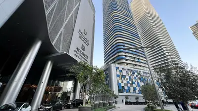 two tall buildings with cars parked in front of them at Damac Maison Mall Street! 2 Bedroom, 2 minute to Dubai Mall! in Dubai